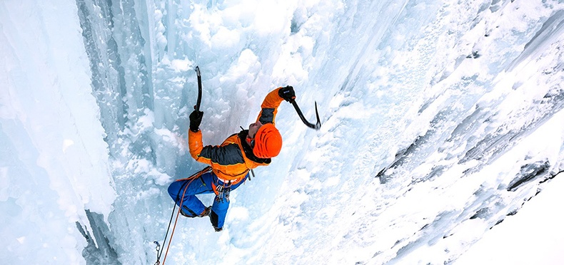 man scaling the side of a glacier