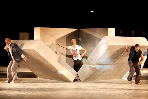 abstract theater play scene of two men holding walls and a third man breaking through 
