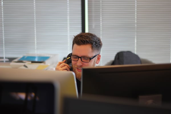 man on phone in front of computer screens