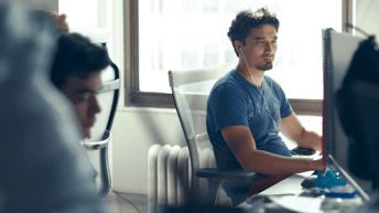 data scientists working on an office desk, looking at screens