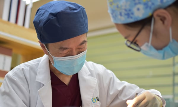 two doctors with face masks operating