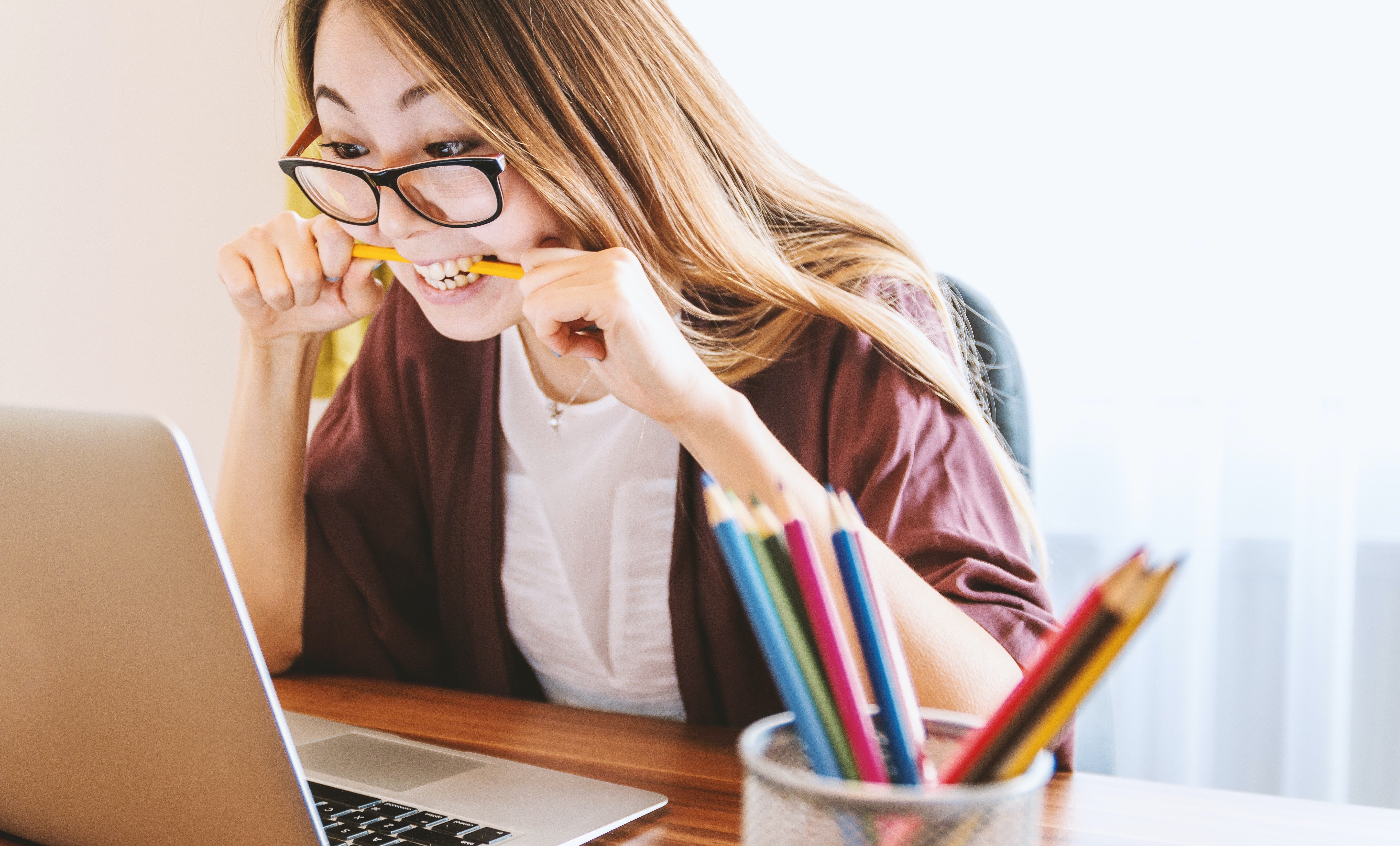 woman in front of a laptop nervous biting a pencil