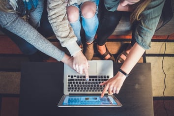 three women pressing keyboard and pointing at laptop screen