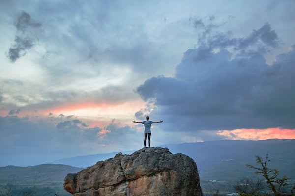 man on mountain with open arms
