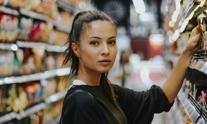 woman grabbing something off a grocery store shelf