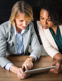 two women huddled over ipad