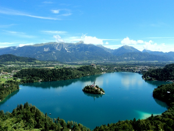 beautiful lake with a small island in the middle surrounded by trees and mountains