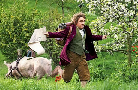 Bilbo Baggins from the Hobbit running in a field with a large pig in the background